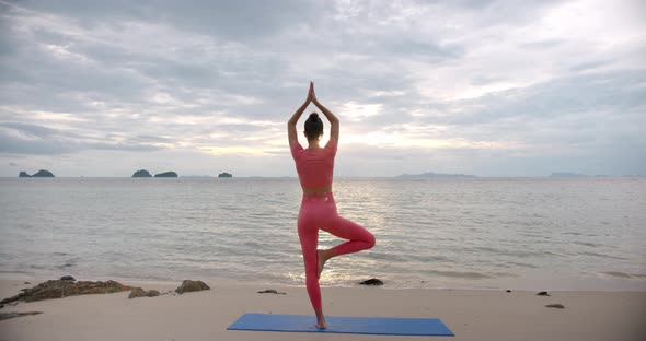 Young Sport Woman Makes Yoga Exercise on the Beach During Sun Set Time