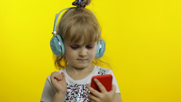Child Dances with Smartphone, Listening To Music on Headphones. Little Kid Girl Dancing, Having Hun