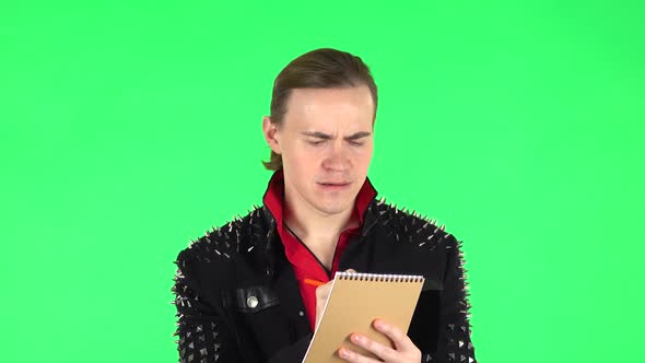 Guy Thinks and Angrily Writes with Pencil in Notebook. Green Screen