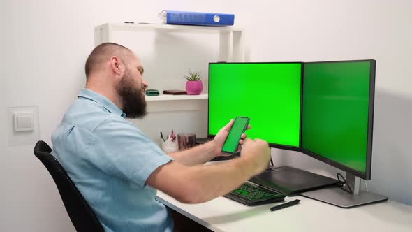 Business Man Using Mobile Phone and Computer with Green Screens Monitors. Work in Office or home