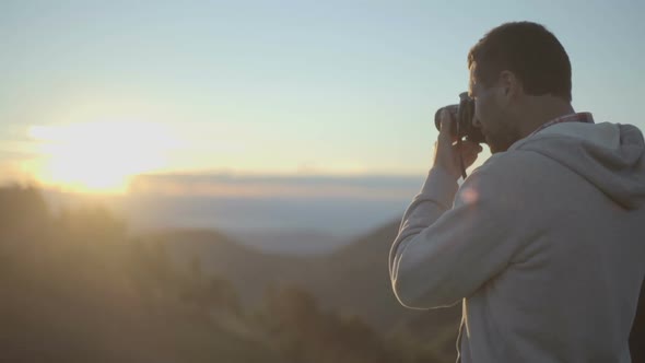 Young Man in Nature Mountain Outdoor Shoot Photos with Camera at Sunrise or Sunset