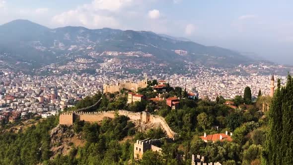 Aerial view of the city and castle hidden in between green trees and plants. Shot pan to right