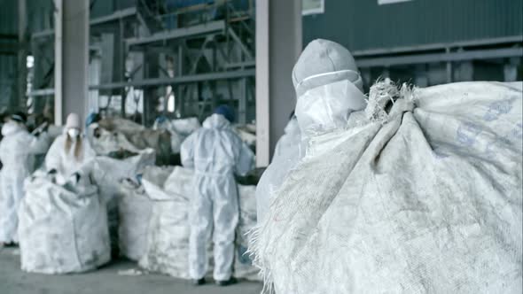 Worker Carrying Bag with Litter at Factory