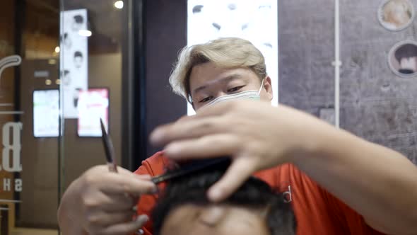 A Barber Cuts Hair to Man From Behind