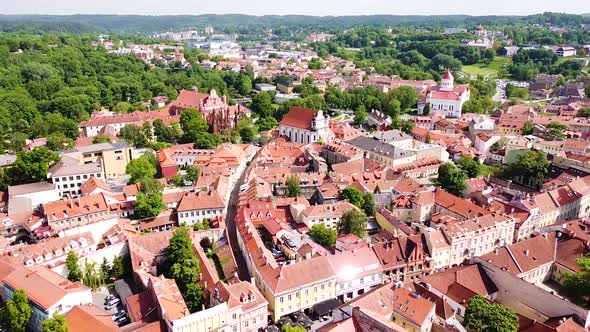 Red and green colors of Vilnius old town on sunny day, aerial fly backward