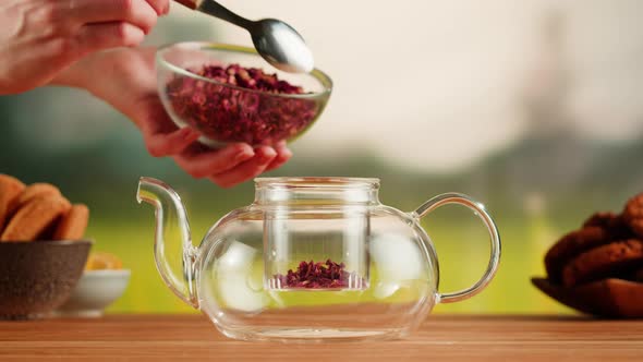 Putting Dry Tea Leaves Into Teapot on a Wooden Table