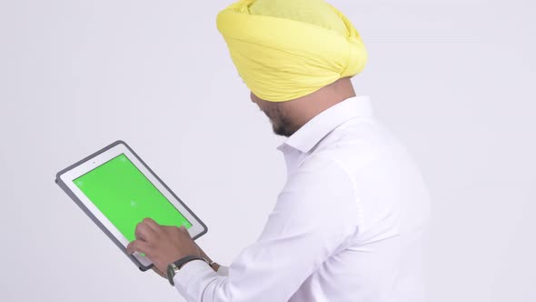 Rear View of Bearded Indian Sikh Businessman Using Digital Tablet