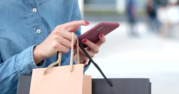 Woman use of mobile phone for shopping with holding shopping bag