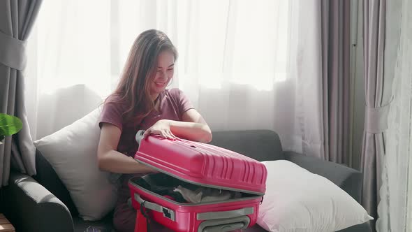 Cute woman happily zipping a suitcase smiling with her passport and credit card