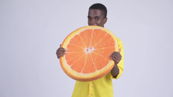 Young Happy African Businessman Biting Orange Pillow As Healthy Concept