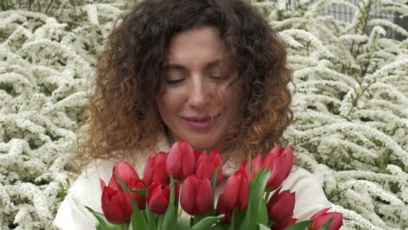 Portrait of a Happy Woman with a Bouquet of Red Tulips