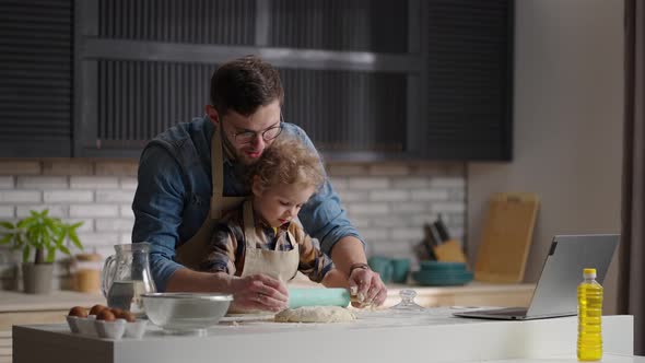 Father and Son at Kitchen Cooking Rolling Out a Dough Spending Time Together at Weekends Medium