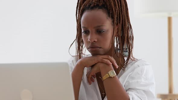 Closeup View of Young African American Woman Looking at Computer Screen at Table in Home Spbi