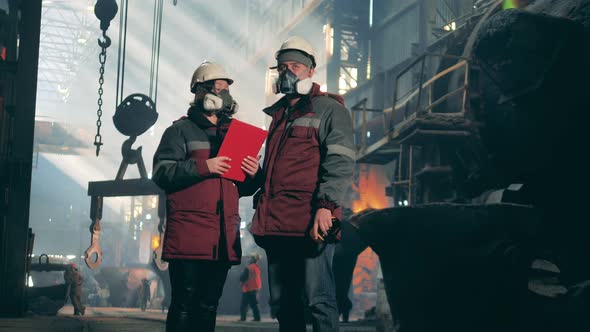A Male and a Female Workers are Talking in the Metallurgical Factory