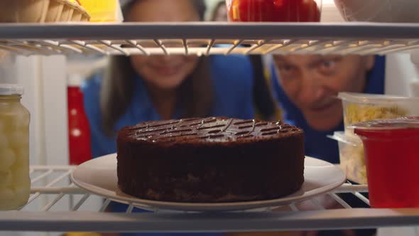 Senior Couple Taking Cake From Refrigerator for Anniversary Party