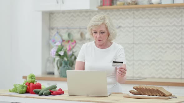 Attractive Senior Old Woman Making Online Payment on Laptop in Kitchen