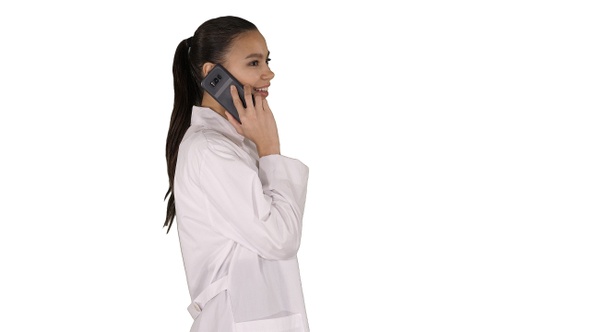 Female Dr smiles while talking on the phone walking