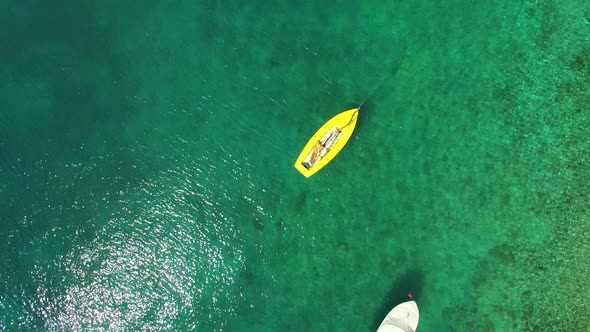 Yellow fishing boat floating in clear green sea alt