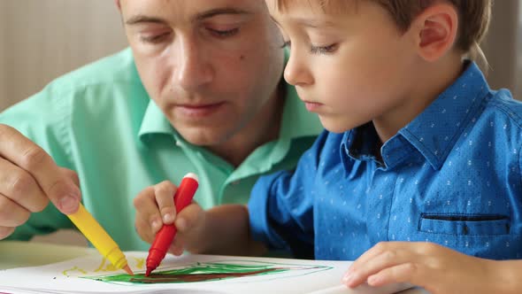 A Mature Father Spends Time with His Young Son, Drawing with Colored pencils.Close Up. The Concept