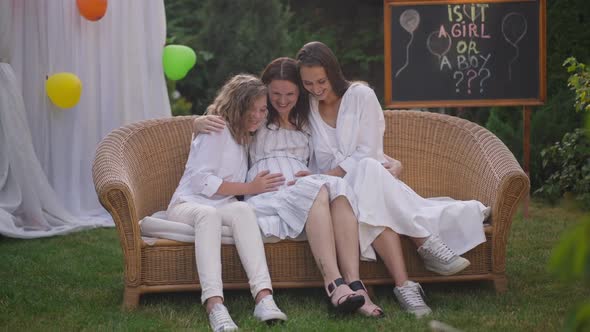 Charming Happy Pregnant Woman and Girls Sitting on Couch on Backyard Celebrating Baby Shower Party