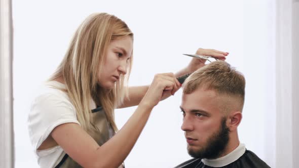 Hairdresser Doing Haircut for Customer Using Scissors in Salon