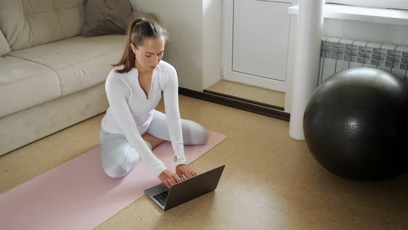 Girl Surfs Internet with Laptop to Find Exercises in Room