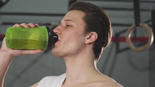 Young Male Athlete Smiling Joyfully Drinking Water