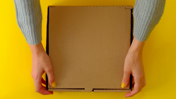 Female Hands Open and Close Box With Donuts On Yellow Background