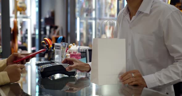 Young woman use smartphone paying over contactless transaction machine