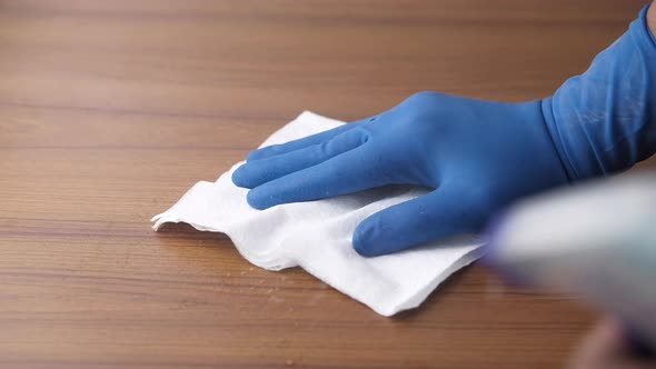 Hand Holding in Blue Gloves and Spray Bottle Cleaning Table .