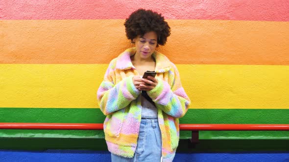 Slow motion young beautiful curly hair black woman indoor leaning on rainbow background