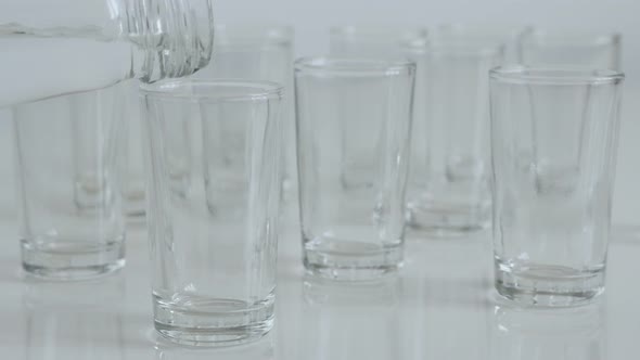 Pouring strong drink  into transparent  glass 4K 2160p 30fps UltraHD footage - Lot of shot glasses o