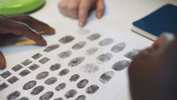 Close Up of Diverse Police Officers Studying Fingerprint Card Working at Police Station