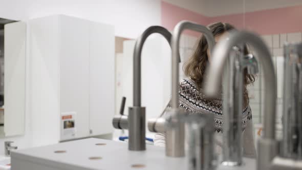 Young Woman Choosing Bathroom Faucet in Hardware Store