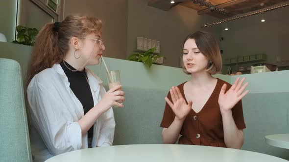 Young Girls Work Remotely in a Cafe on the Summer Terrace