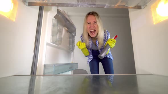 A woman looks inside the refrigerator and screams. Stress. cleaning.