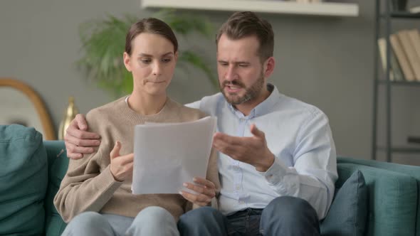 Couple Having Failure While Reading Documents on Sofa