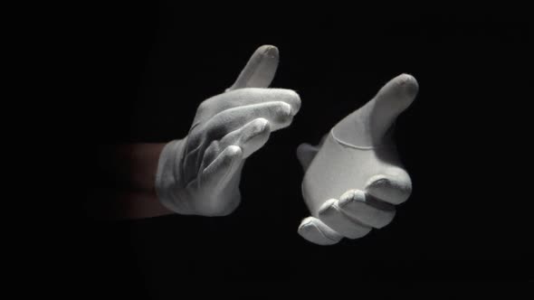 Gloved hands clapping on black background close up