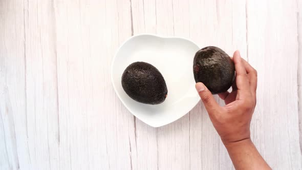 Hand Pick Avocado From a Plate on Wooden Table