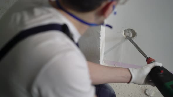 A Worker Builder on a Construction Site with a Punch Makes Repairs to an Apartment or a House