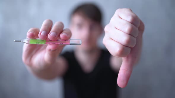 A Young Man Shows a High Temperature on Medical Thermometer and Dislike. Symptoms of Coronavirus