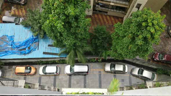 Rain water droplets falling from building ceiling on the cars parked below the building