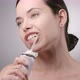 Young Woman with Dark Brown Hair Cleaning Teeth with Water Flosser and Smiling - VideoHive Item for Sale
