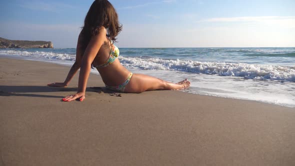 Young Girl in Bikini Lying on Sea Beach and Sunbathing. Unrecognizable Woman Relaxing on Sea Shore