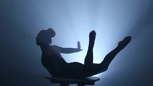 Gymnast on the Table Sits on the Splits, Smoke Background, Slow Motion, Silhouette