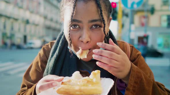 Portrait of young woman eating pastry outdoors, Italy