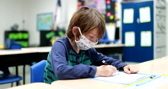 As students return to school during the COVID 19 Coronavirus pandemic a young boy wearing a mask and