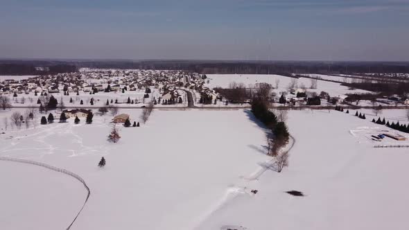 Townscape Near Deep Snow Farmland With Cars Traveling On Countryroad In Flat Rock, Michigan. - Aeria