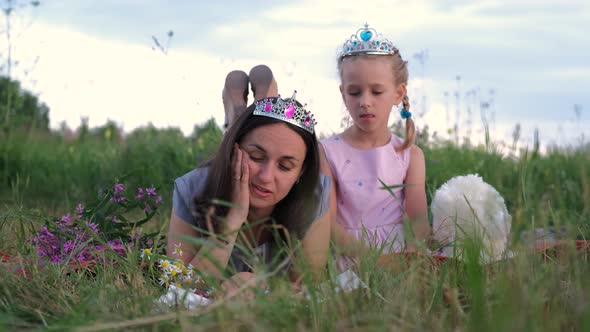 Young Mother Reading Book to Daughter Outdoors