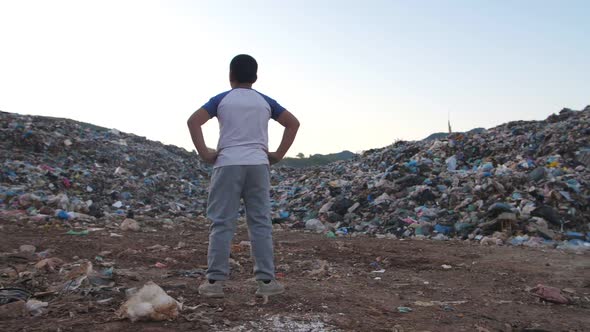 Young Boy Stands And Looking At Garbage Pile